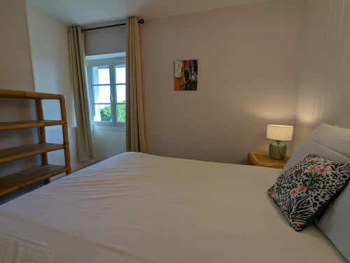 Chambre lumineuse au Domaine du Faure avec lit blanc, vue sur jardin, étagères en bois et lampe moderne à Chadurie, France