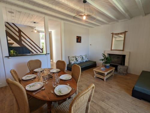 Vaste espace salle à manger et séjour au Gîte Le Bambou du Domaine du Faure avec table en bois, cheminée et vue sur le jardin