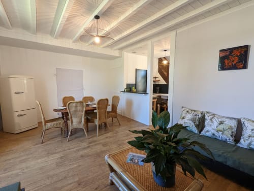 Séjour ouvert et moderne au Gîte Le Bambou du Domaine du Faure avec table à manger, canapé, kitchenette et vue sur jardin