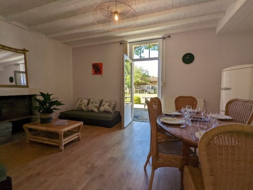 Séjour spacieux et salle à manger du Gîte Le Bambou avec vue sur le jardin, canapé, table à manger, parquet et terrasse