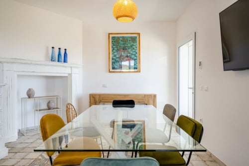 Modern dining room at Top Villas Sardinia with glass table, colorful chairs, and framed artwork