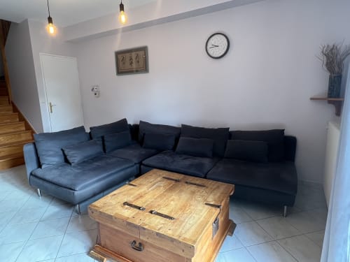 Espace lounge moderne au Gîte Le Prune du Domaine du Faure, avec canapé bleu foncé, table-coffre en bois et luminaire suspendu