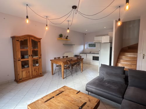 Spacieux séjour du Domaine du Faure avec table à manger, meuble en bois, canapé sombre et luminaires suspendus modernes