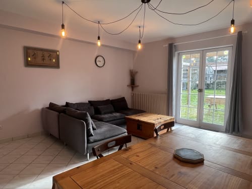Séjour moderne au Domaine du Faure avec canapé noir, mobilier en bois et portes vitrées donnant sur le jardin