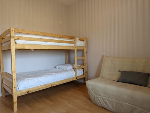 Lit superposé en bois avec literie blanche à côté d'un canapé beige dans la chambre du Domaine du Faure, Chadurie.