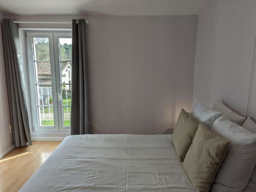 Chambre lumineuse au gîte Domaine du Faure à Chadurie avec vue sur jardin, portes-fenêtres, parquet et lit confortable