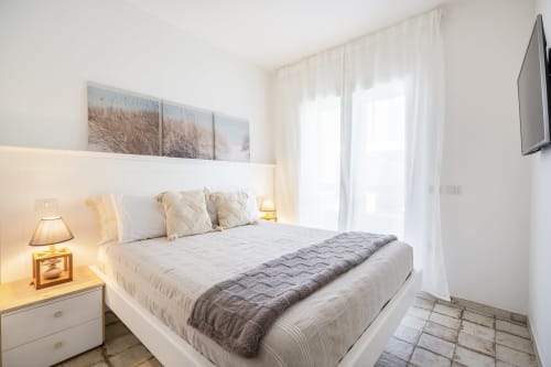 Bright modern bedroom at Top Villas Sardinia with white bed, soft lighting, and coastal decor in Quartu Sant'Elena