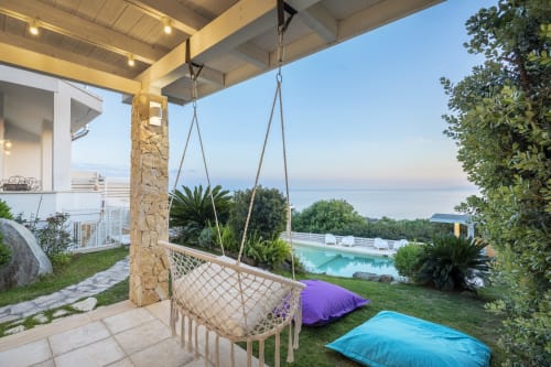 Hanging macramé chair on patio overlooking private pool and Sardinian sea at Villa Fiorenza