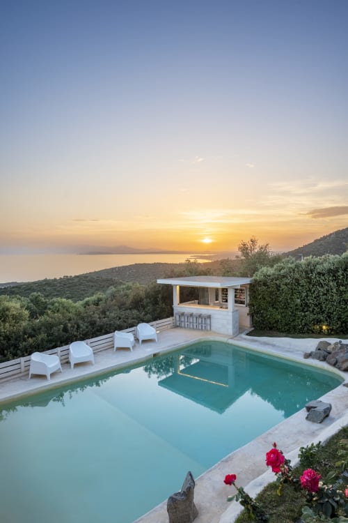 Villa Fiorenza in Sardinia with turquoise pool, white loungers, sunset sea view, and outdoor bar at dusk