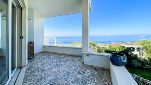 Spacious terrace of Villa Fiorenza in Sardinia with sea views, decorative tiled floor, white columns, and blue Mediterranean