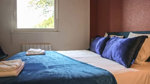Geräumiges Schlafzimmer in der Villa Pré d'Oro mit blauer Bettwäsche, violetten Kissen, Bergblick und modernem Komfort in Amage