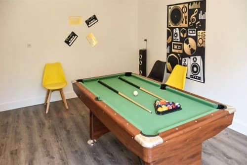 Freizeitraum mit Billardtisch, gelben Stühlen und musikthematischer Wandkunst in der Villa Pré d'Oro