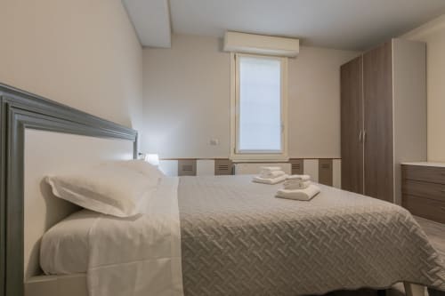 Camera moderna dell'Hotel Prince Garda a Serniga con letto matrimoniale, armadi in legno e luce naturale dalla finestra