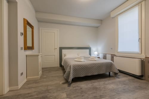 Camera spaziosa dell'Hotel Prince Garda a Serniga con letto matrimoniale, pavimento in legno, specchio e ampia finestra