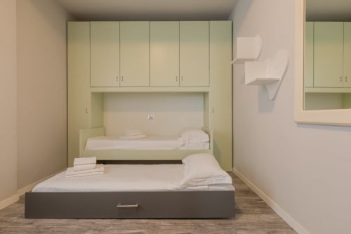 Camera compatta dell'hotel Prince Garda a Serniga con letto integrato e scaffali per la conservazione