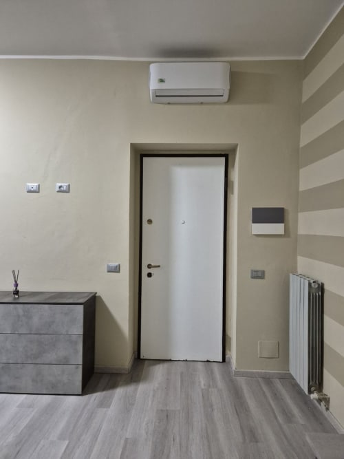 Ingresso moderno dell'appartamento Mia Monza Living in Italy con porta bianca, unità split AC e pareti beige minimaliste