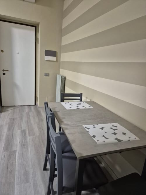 Appartamento moderno Mia Monza con parete a righe, tavolo da pranzo e sedie nere a Monza, Italia