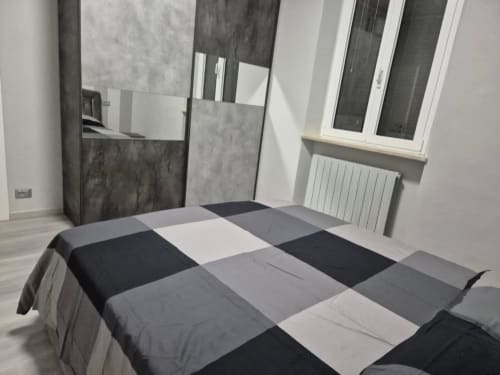 Camera moderna di Mia Experience Monza con copriletto patchwork, specchio, finestra e termosifone