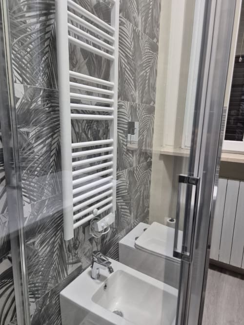 Bagno moderno nell'appartamento Mia Monza Living con portasciugamani bianco, piastrelle a motivo palma, lavabo e box doccia