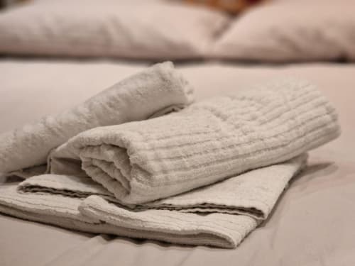 Asciugamani in lino crema piegati ordinatamente sul letto di Mia Experience, una boutique apartment a Monza, Italia