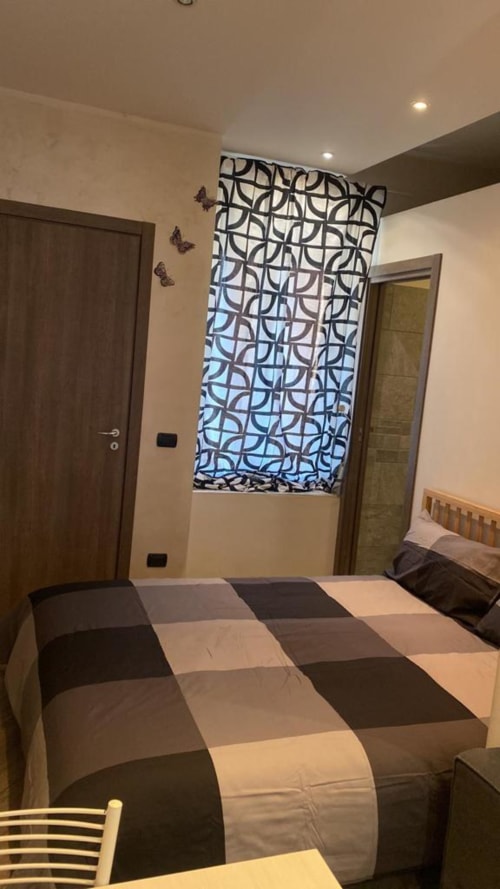 Camera da letto Mia Monza Suite con biancheria a righe, pannello finestra decorato e arredi moderni nell'appartamento di Monza