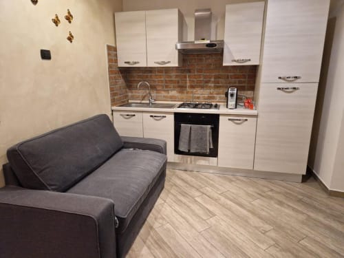 Mia Monza Suite a Monza con moderna angolo cottura, ante bianche, rivestimento in mattoni e comoda zona salotto