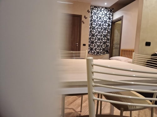 Camera moderna della Mia Monza Suite con letto bianco, specchio, arte geometrica a parete e arredi contemporanei