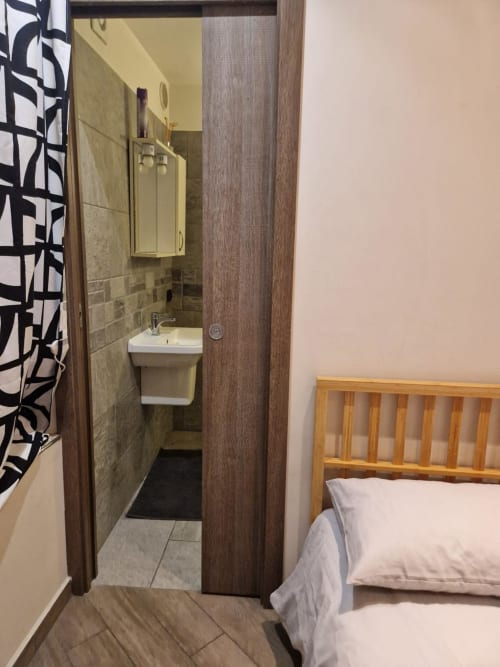 Ingresso del bagno della Mia Monza Suite con lavabo e doccia, adiacente alla camera da letto presso Mia Experience Monza