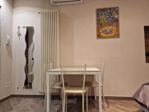 Zona pranzo dell'appartamento Mia Monza Suite con tavolo bianco, sedie e radiatore nel BnB di Monza