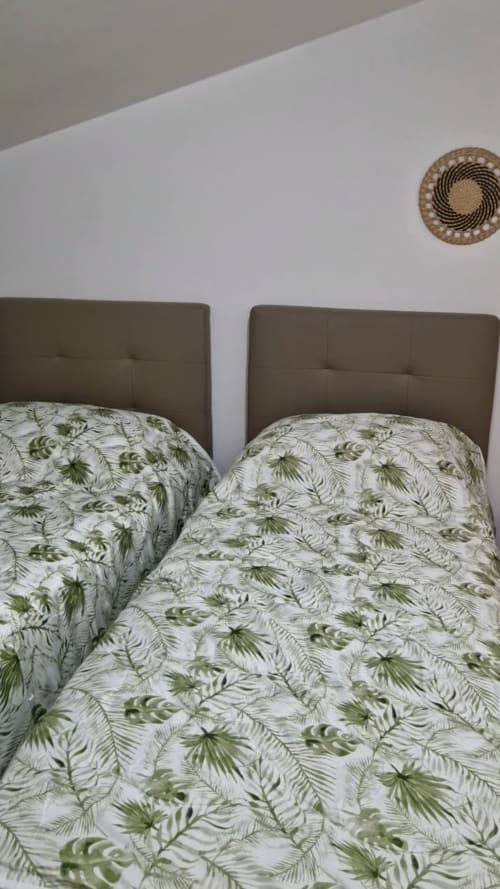 Two twin beds with green tropical leaf bedding in Tales of Abruzzo apartment, Atessa