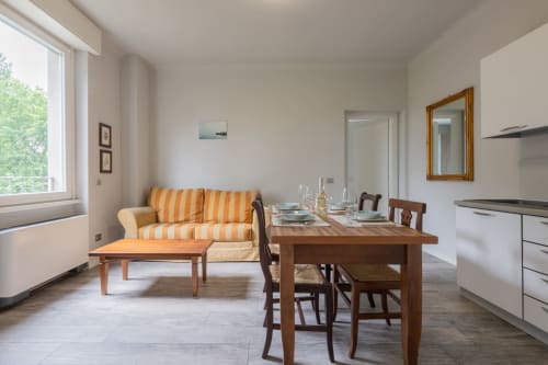 Zona living open-plan Prince Garda con divano rigato, tavolo da pranzo e cucina a Serniga