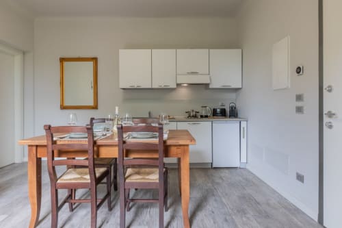 Cucina e zona pranzo open-plan a Prince Garda con tavolo in legno, armadiature bianche e elettrodomestici moderni a Serniga
