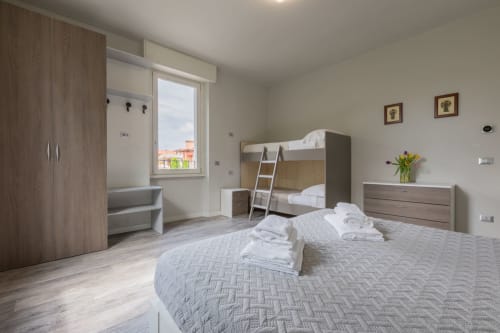 Camera moderna presso l'hotel Prince Garda a Serniga con letto a castello, letto singolo, mobili in legno e vista sul lago