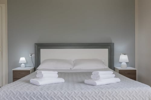 Camera moderna dell'Hotel Prince Garda a Serniga con testata specchiata, cuscini bianchi, asciugamani ripiegati e lampade comodino
