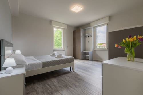 Camera moderna dell'hotel Prince Garda a Serniga con letto, scrivania, finestre e tulipani freschi