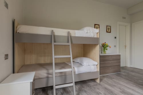 Camera con letto a castello moderno dell'Hotel Prince Garda a Serniga con arredamenti in legno, biancheria bianca e pavimenti in parquet
