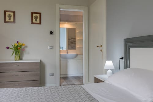 Camera moderna dell'Hotel Prince Garda a Serniga con bagno interno, biancheria bianca e fiori freschi sul comò
