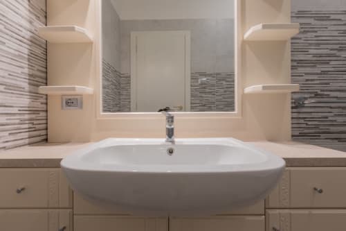 Bagno moderno presso Prince Garda con doppio lavabo, specchio illuminato, rivestimenti in piastrelle righe e piano in marmo