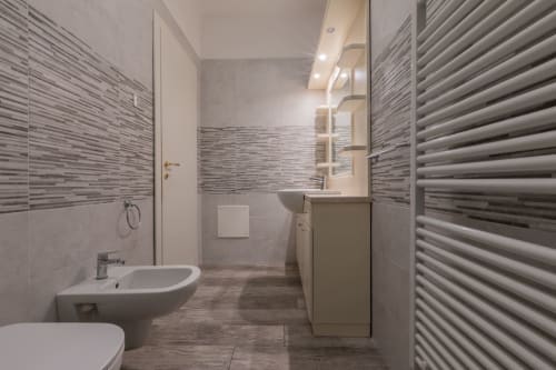 Bagno moderno all'Hotel Prince Garda di Serniga con piastrelle rigate, lavabo, bidet e scaldalavagni.