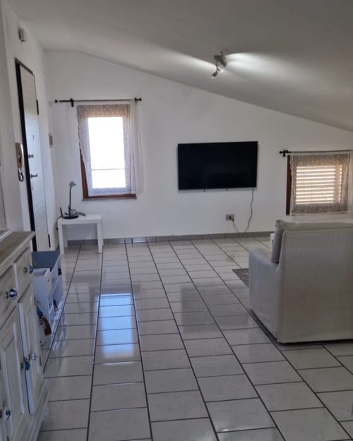 Spacious apartment living area at Tales of Abruzzo with tiled floor, flat-screen TV, and windows in Atessa