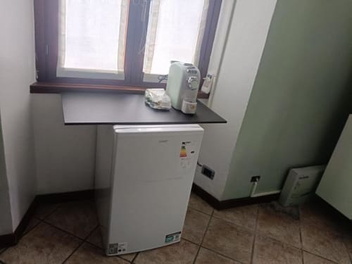 Angolo cottura compatto nella Luna Deluxe Room di Mia Experience BnB a Monza, con frigorifero bianco e piano di lavoro