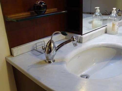 Lavabo in marmo con rubinetto cromato e articoli da toilette nella B&B Mia Experience di Monza
