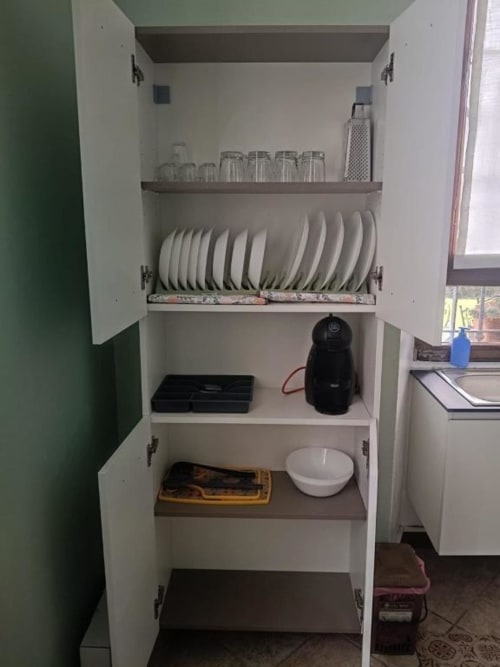Credenza della cucina aperta presso la Mia Experience BnB a Monza con stoviglie, bicchieri, elettrodomestici e utensili da cucina ordinatamente riposti