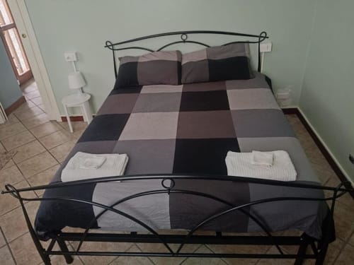 Spaziosa camera deluxe presso il B&B Mia Experience a Monza con letto in metallo, biancheria a quadri e pavimento piastrellato.