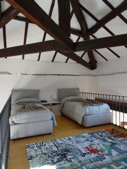 Suite familiare Mia Experience deluxe con travi in legno a vista, due letti, tappeto colorato e pavimento in legno a Monza