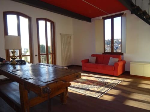 Suite Familiare Alba Deluxe presso Mia Experience a Monza con divano rosso, tavolo in legno e balcone con vista sul giardino