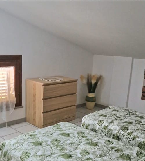 Bedroom at Tales of Abruzzo, Atessa with twin beds, wooden dresser, potted plant, and sloped ceiling