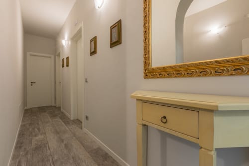 Corridoio moderno dell'hotel Prince Garda a Serniga con pavimento in legno, porte bianche, specchio ornamentale e consolle