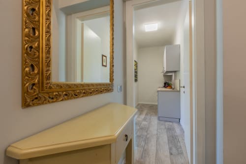 Corridoio dell'hotel Prince Garda a Serniga con specchio dorato ornamentale, asse da stiro e angolo cottura