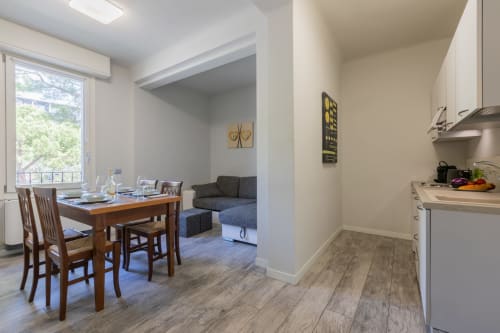 Cucina moderna e zona pranzo dell'hotel Prince Garda a Serniga con tavolo in legno, cabinetry bianca e vista dello spazio living